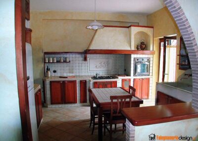 Cucina in muratura con ante e tavoli in legno